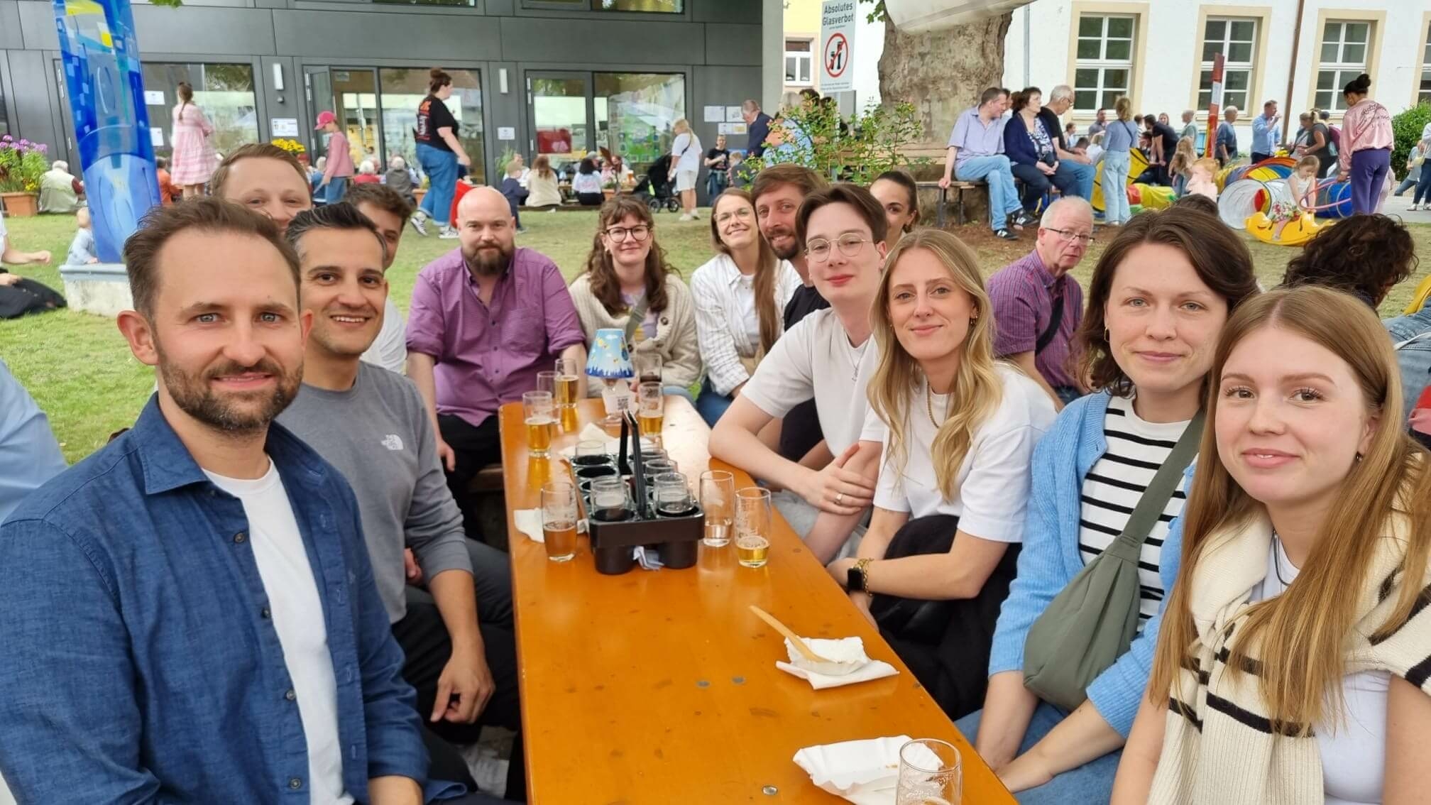 Teamfoto beim Outdoor-Event mit Menschen im Hintergrund